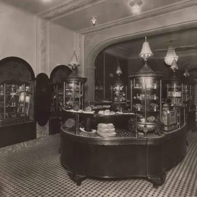Historic interior of Myšák pastry shop with central counter and display cabinets.