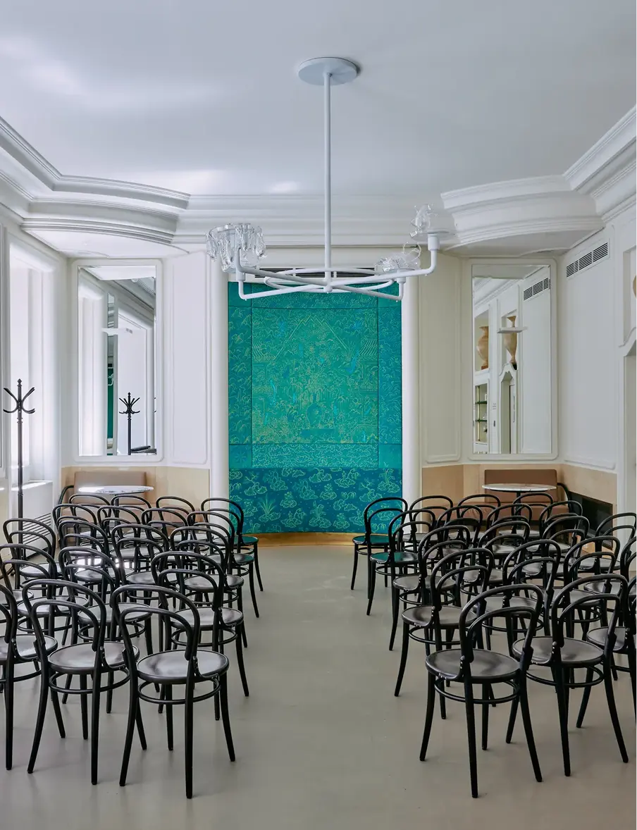 Interior of Myšák pastry shop with rows of black chairs and a turquoise decorative wall.