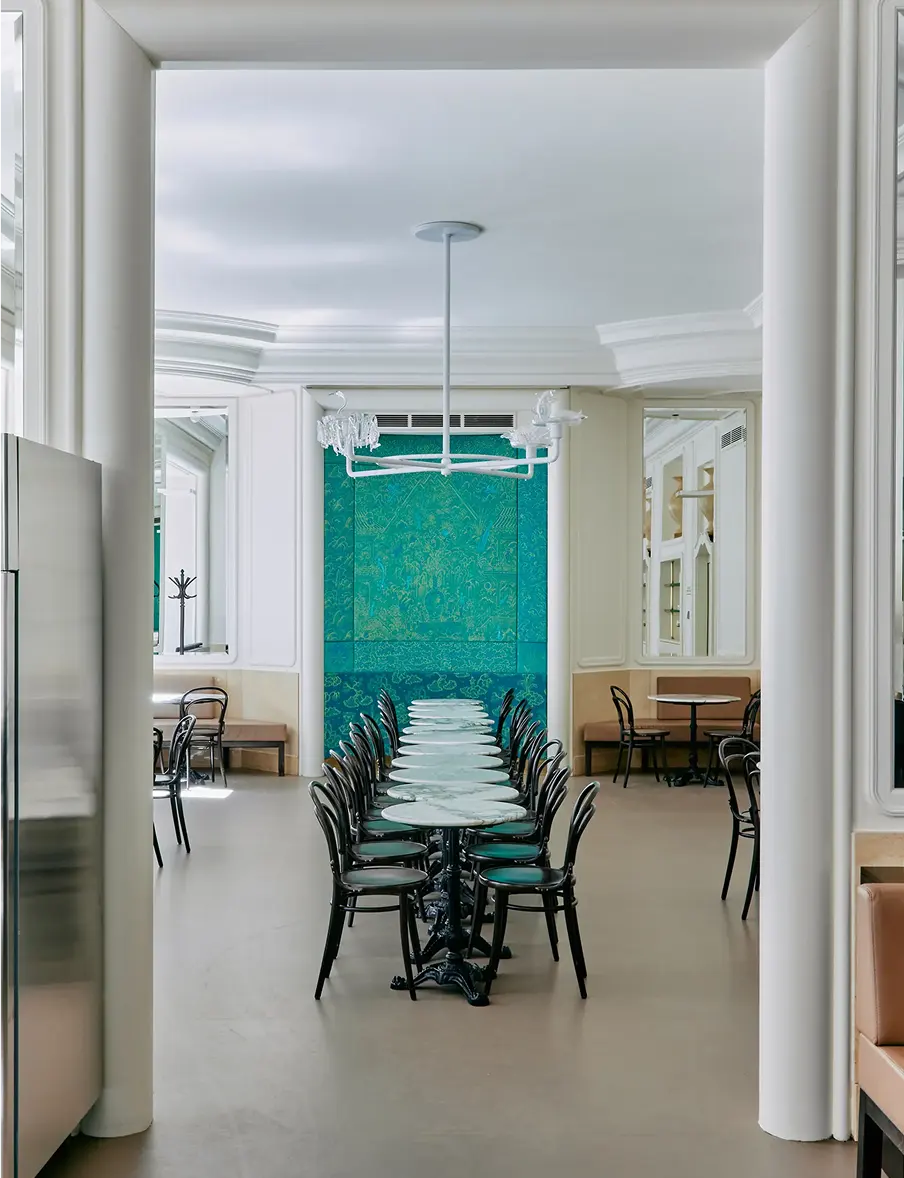 Interior of Myšák pastry shop with marble tables and a turquoise wall.