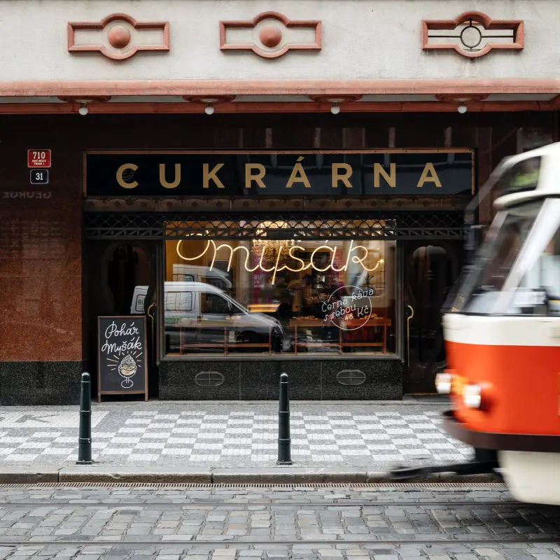Exterior of Myšák pastry shop with a passing tram.