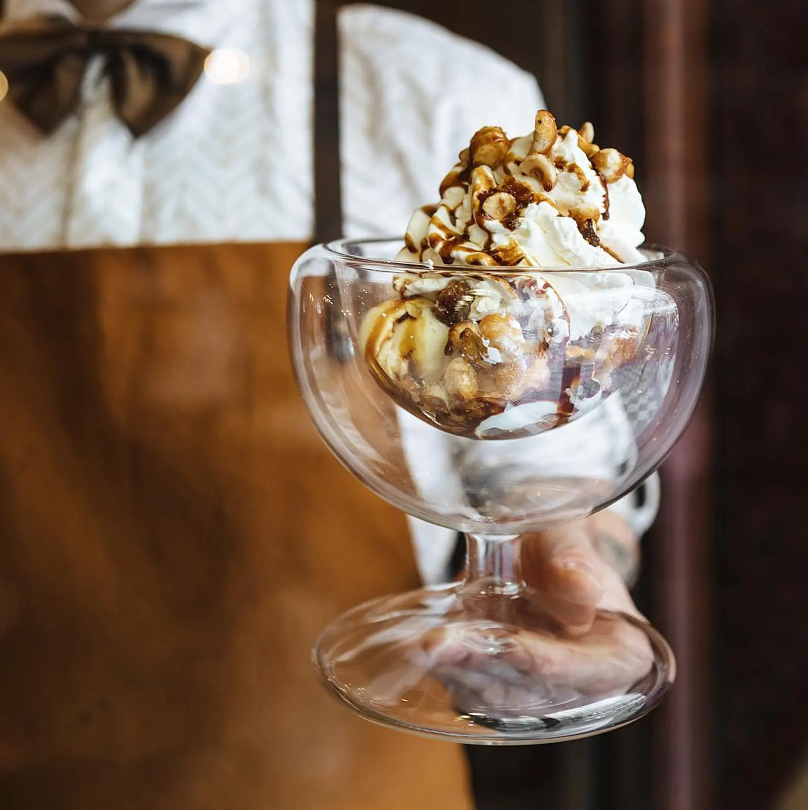 Ice cream sundae with whipped cream and nuts in a pastry shop.